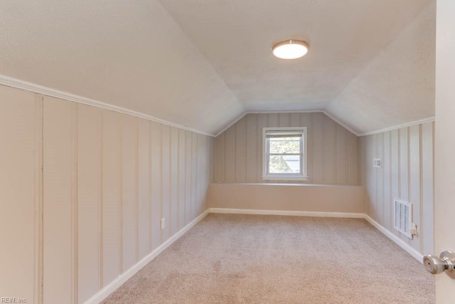 bonus room with vaulted ceiling, baseboards, visible vents, and light colored carpet