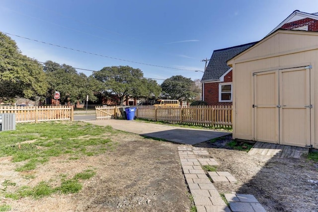 view of yard with an outbuilding, a storage unit, central AC unit, and fence