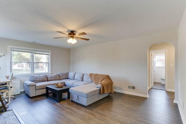 living room with baseboards, visible vents, arched walkways, ceiling fan, and wood finished floors