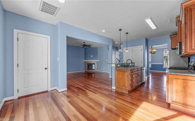 kitchen featuring visible vents, brown cabinetry, and a glass covered fireplace