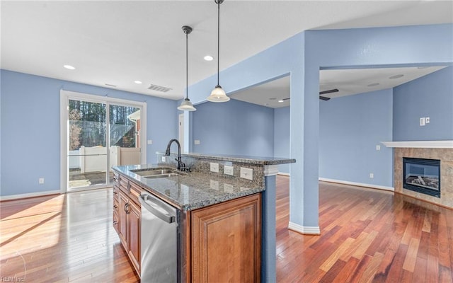 kitchen featuring a sink, visible vents, open floor plan, brown cabinets, and dishwasher