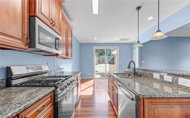 kitchen featuring light wood finished floors, visible vents, brown cabinets, stainless steel appliances, and a sink