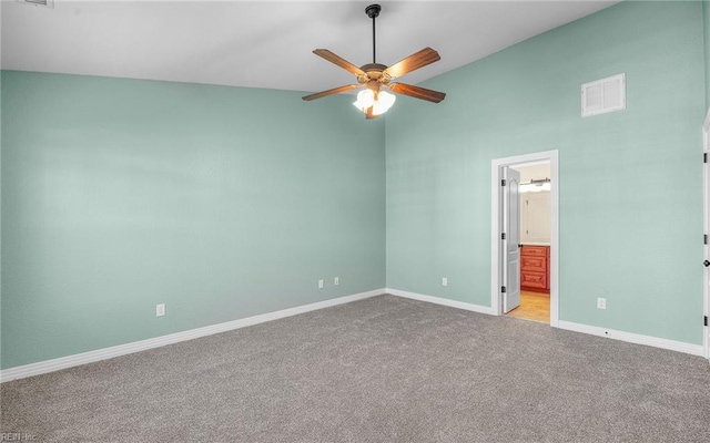 carpeted spare room featuring baseboards, vaulted ceiling, visible vents, and ceiling fan