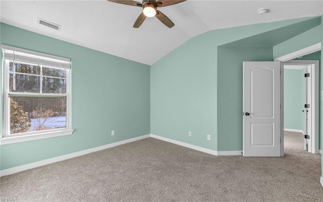 carpeted spare room with vaulted ceiling, ceiling fan, visible vents, and baseboards