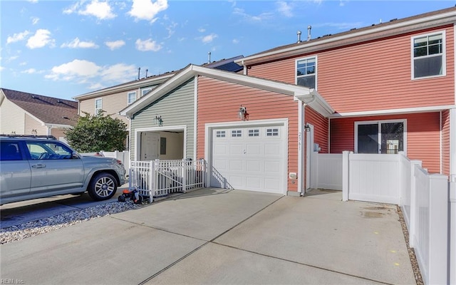 view of side of property with an attached garage, driveway, and fence