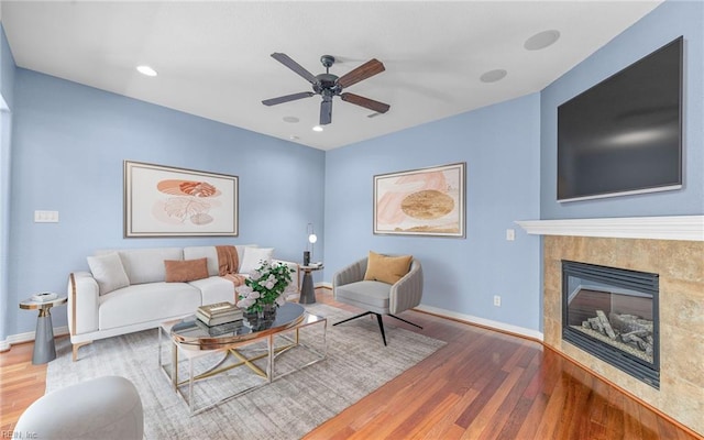 living room with recessed lighting, a fireplace, wood finished floors, a ceiling fan, and baseboards