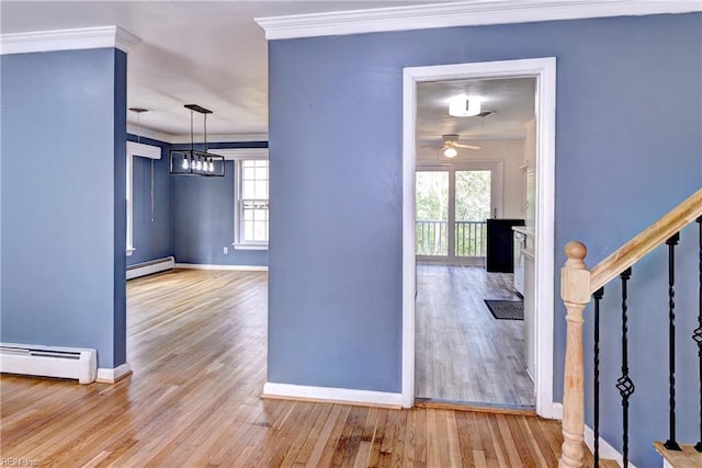 entrance foyer with a healthy amount of sunlight, crown molding, baseboard heating, and stairs