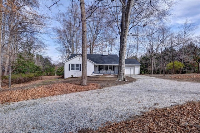 ranch-style house with a garage, gravel driveway, and a chimney