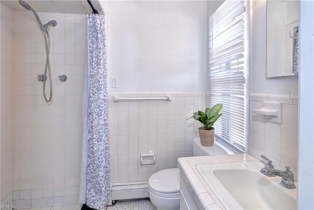 full bath featuring tiled shower, a sink, toilet, and tile walls