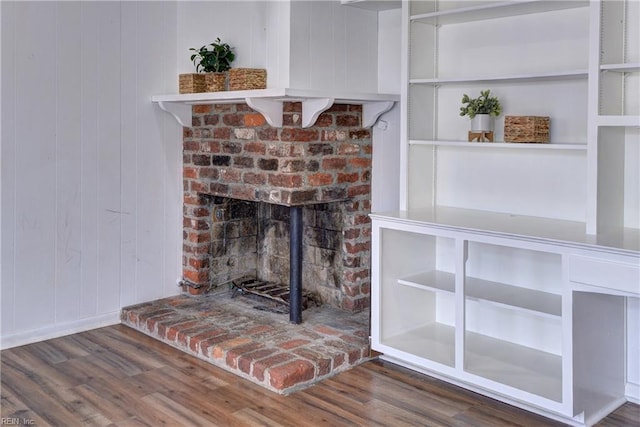 room details with a brick fireplace, wood walls, and wood finished floors