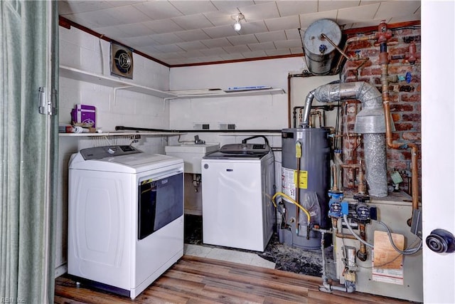 washroom with gas water heater, visible vents, washing machine and dryer, wood finished floors, and laundry area