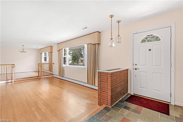 foyer entrance with a baseboard radiator, visible vents, wood finished floors, a chandelier, and baseboards