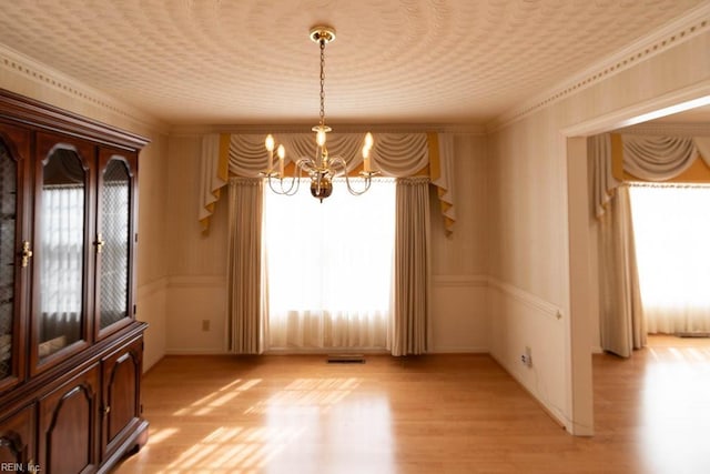 unfurnished dining area with light wood-style floors, visible vents, and a notable chandelier