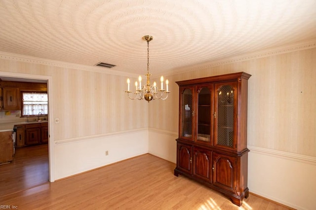 unfurnished dining area with light wood-style floors, visible vents, a sink, and a notable chandelier