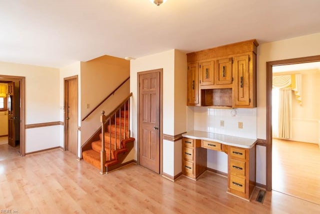 kitchen featuring light wood-type flooring, baseboards, light countertops, and decorative backsplash