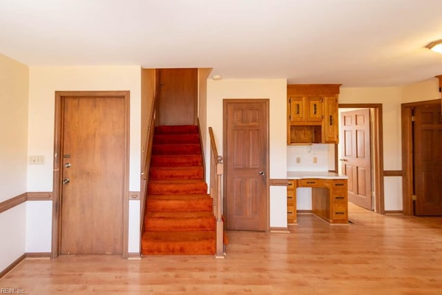 kitchen featuring light wood finished floors, tasteful backsplash, baseboards, and light countertops