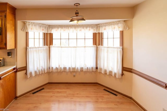 spare room with light wood finished floors, a wealth of natural light, and visible vents