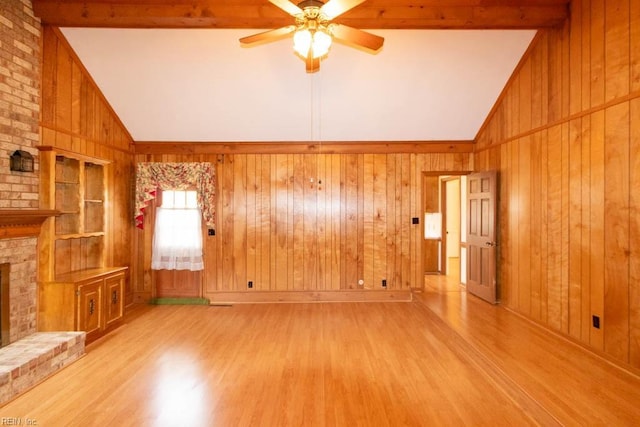 unfurnished living room featuring vaulted ceiling with beams, a brick fireplace, wood finished floors, and wooden walls