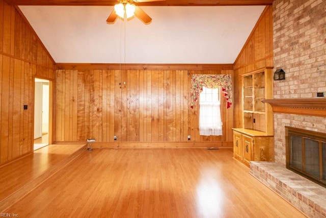 unfurnished living room with lofted ceiling, a brick fireplace, and wood finished floors