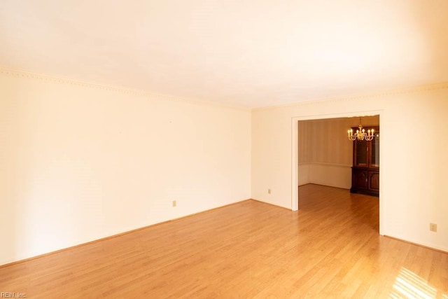 spare room with a chandelier and light wood-style flooring