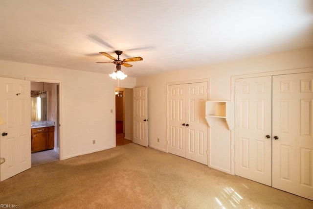 unfurnished bedroom featuring light carpet, baseboards, connected bathroom, and multiple closets