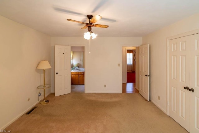 unfurnished bedroom featuring a closet, light colored carpet, visible vents, a ceiling fan, and baseboards