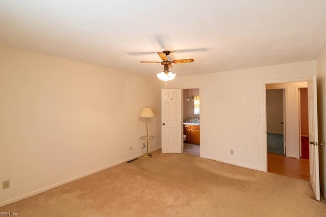 unfurnished bedroom featuring light carpet, ensuite bathroom, and baseboards