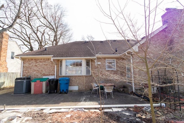 rear view of property with brick siding, a patio, a shingled roof, fence, and cooling unit