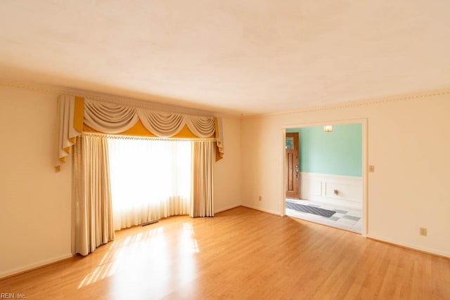 unfurnished room featuring light wood-style flooring and wainscoting