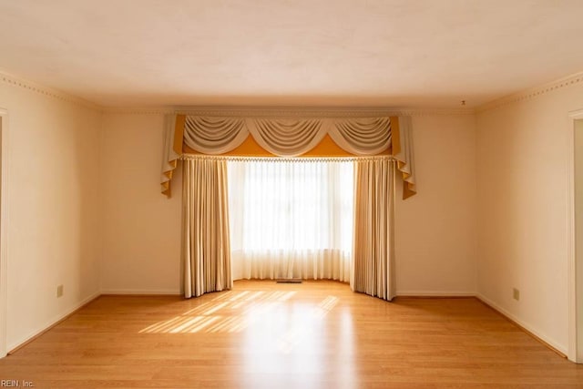 unfurnished room featuring light wood-style flooring, baseboards, and crown molding