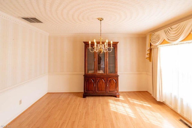 empty room featuring visible vents, a notable chandelier, and light wood-style flooring