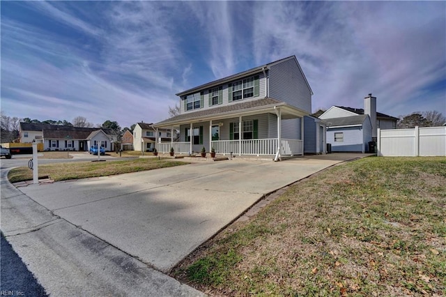 view of front of property featuring covered porch, driveway, a front lawn, and fence