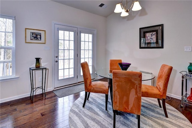 dining area featuring visible vents, plenty of natural light, an inviting chandelier, and wood finished floors