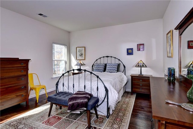 bedroom featuring baseboards, visible vents, and wood finished floors