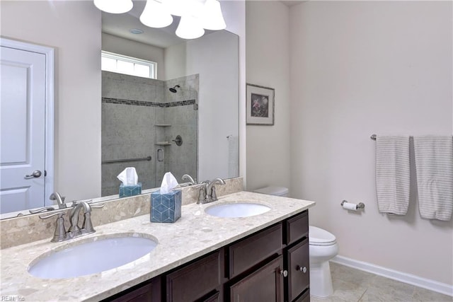 bathroom featuring a sink, a tile shower, toilet, and double vanity