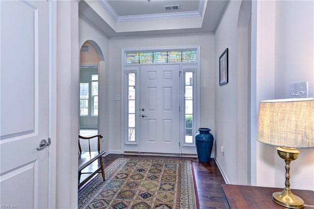 foyer entrance with arched walkways, visible vents, baseboards, dark wood-style floors, and crown molding