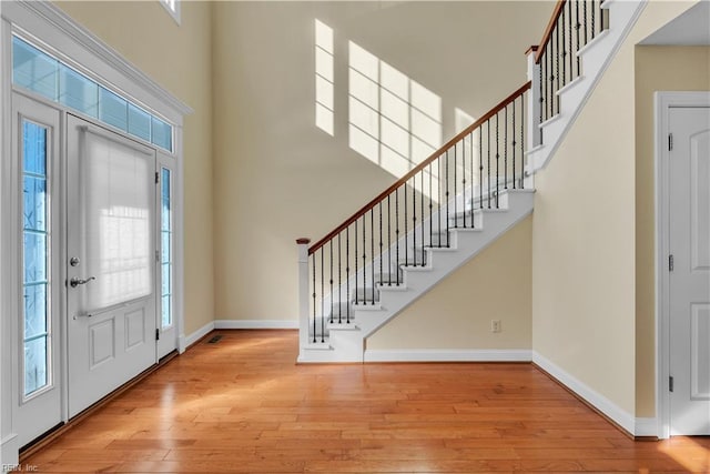 entrance foyer featuring baseboards, a towering ceiling, and hardwood / wood-style floors