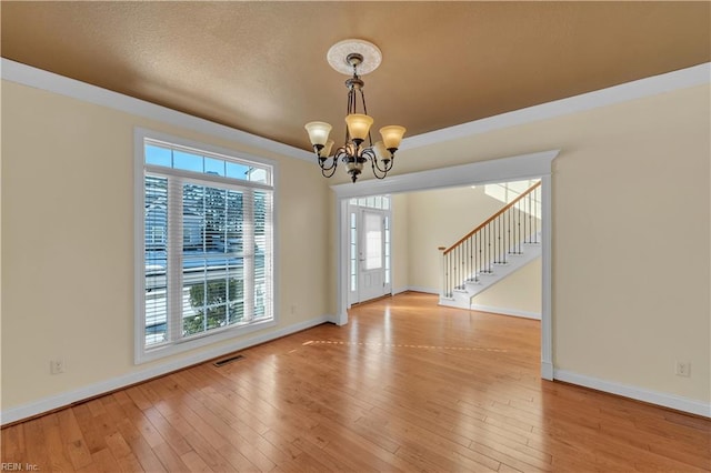 unfurnished dining area with light wood finished floors, visible vents, a chandelier, baseboards, and stairs