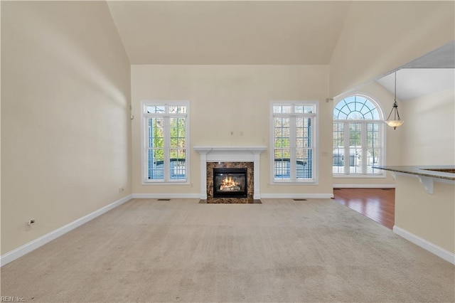 unfurnished living room with carpet floors, a fireplace, baseboards, and vaulted ceiling