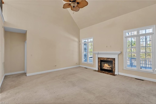 unfurnished living room featuring high vaulted ceiling, a premium fireplace, carpet flooring, and baseboards