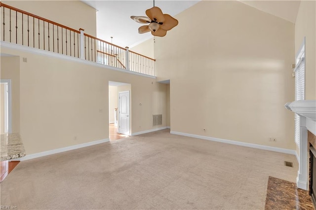 unfurnished living room featuring a ceiling fan, a fireplace with flush hearth, visible vents, and light colored carpet