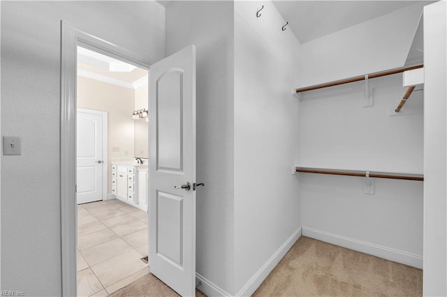 walk in closet featuring light carpet, a sink, and light tile patterned flooring