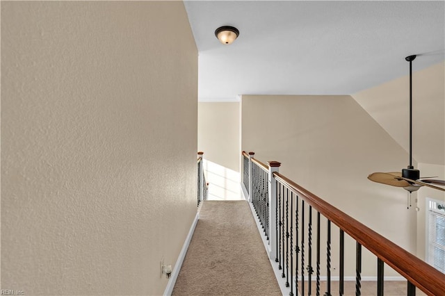 hallway with baseboards, vaulted ceiling, carpet flooring, and an upstairs landing