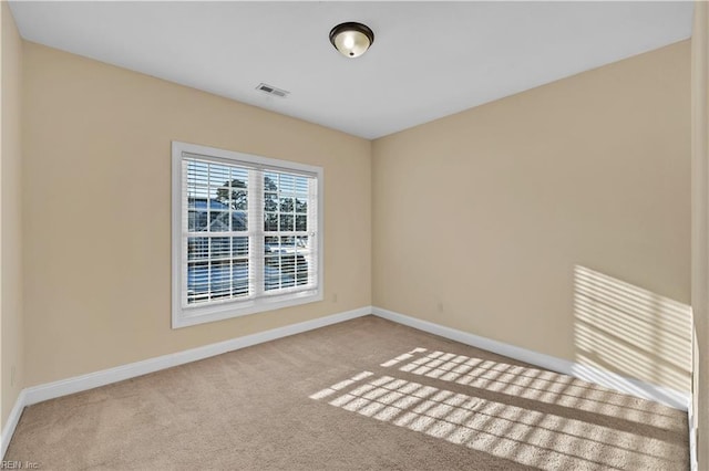 carpeted spare room featuring visible vents and baseboards