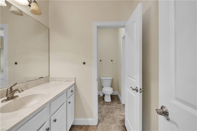 bathroom with vanity, toilet, and baseboards