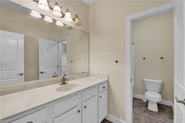 bathroom with baseboards, vanity, and toilet