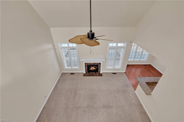 unfurnished living room featuring lofted ceiling, ceiling fan, a fireplace, and baseboards