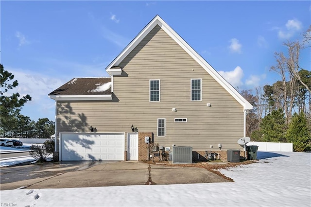 rear view of house featuring a garage, cooling unit, and concrete driveway