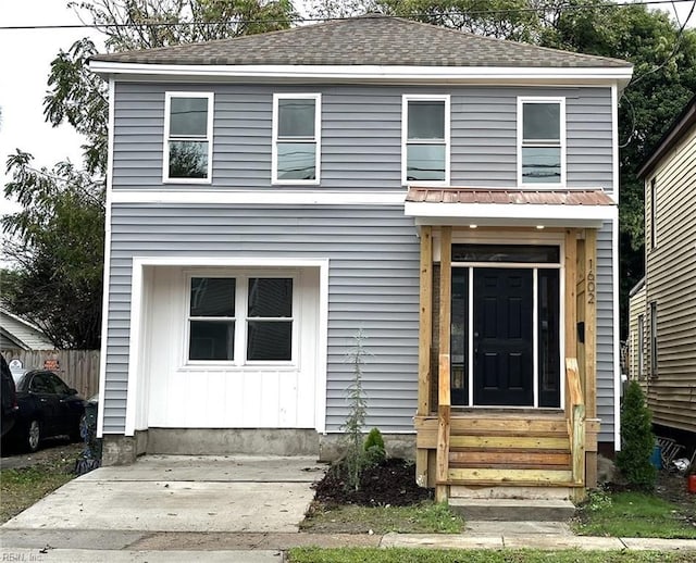 traditional home featuring entry steps, roof with shingles, and board and batten siding