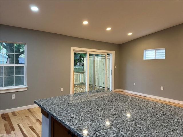 kitchen with light wood-style floors, recessed lighting, vaulted ceiling, and dark stone countertops